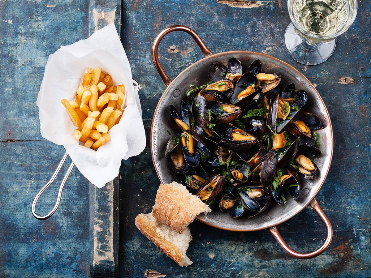 Mussels In Copper Cooking Dish And French Fries On Blue Backgrou