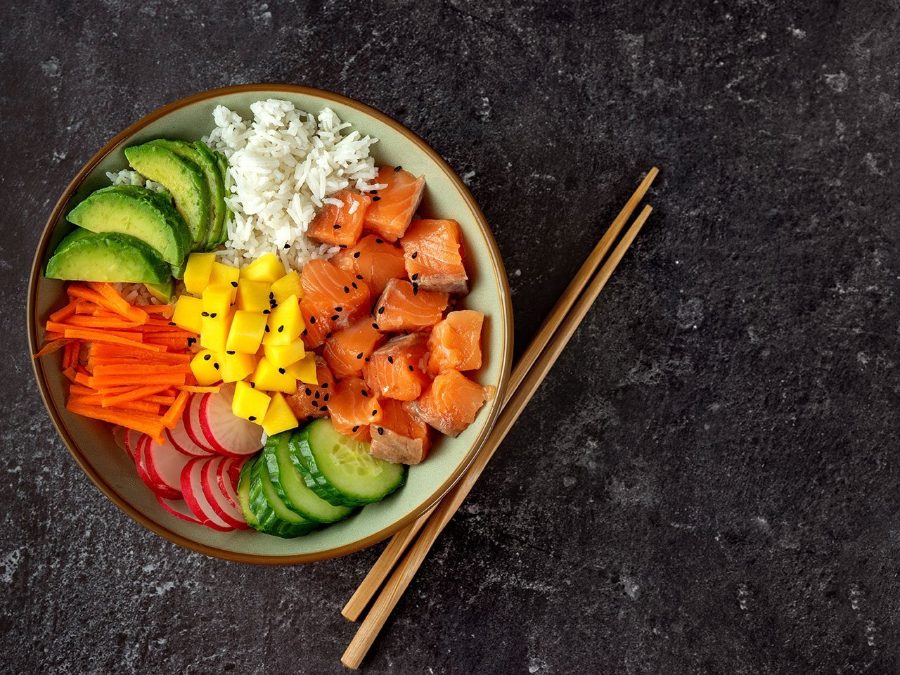Top View Of Poke Bowl With Salmon And Avocado On Dark Background