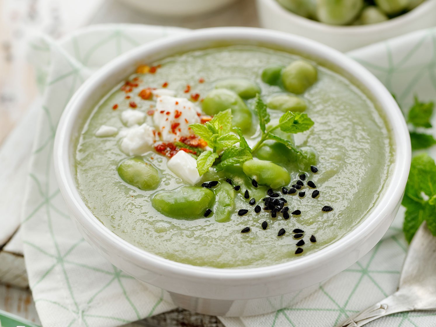 Broad Bean Soup With Fresh Mint And Feta Cheese In A White Bowl
