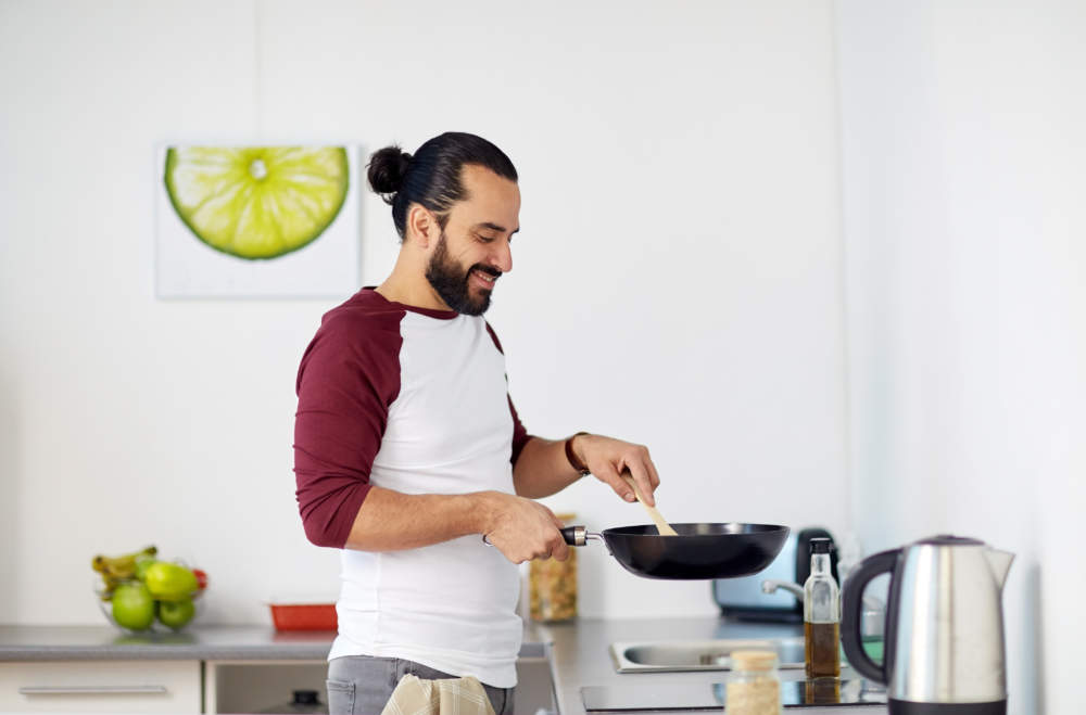 Man With Frying Pan Cooking Food At Home Kitchen