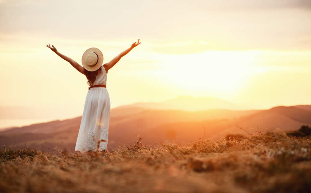 Happy Woman Standing With Her Back On Sunset In Nature