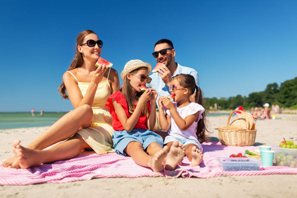 Happy Family Having Picnic On Summer Beach