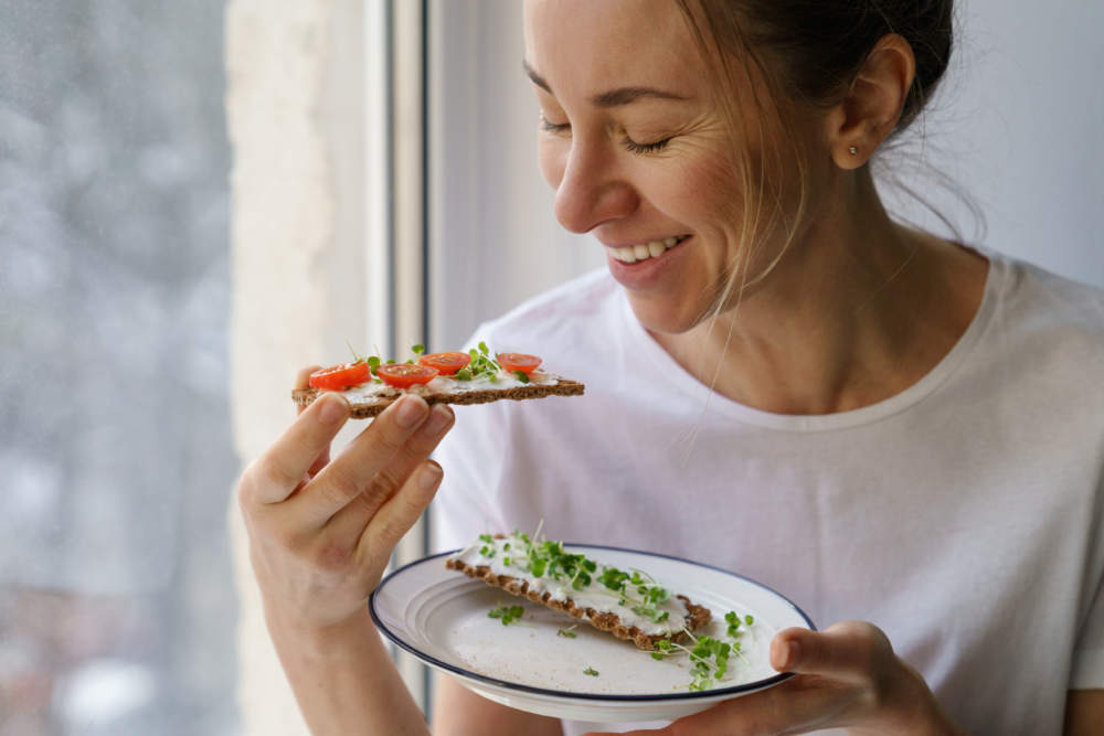 Woman Eating Rye Crisp Bread With Creamy Vegetarian Cheese Tofu, Tomato, Micro Greens. Healthy Food