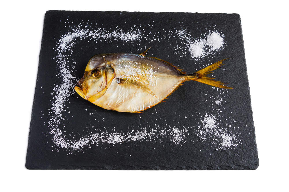 Dry Fish On Black Stone. Isolated On White Background.