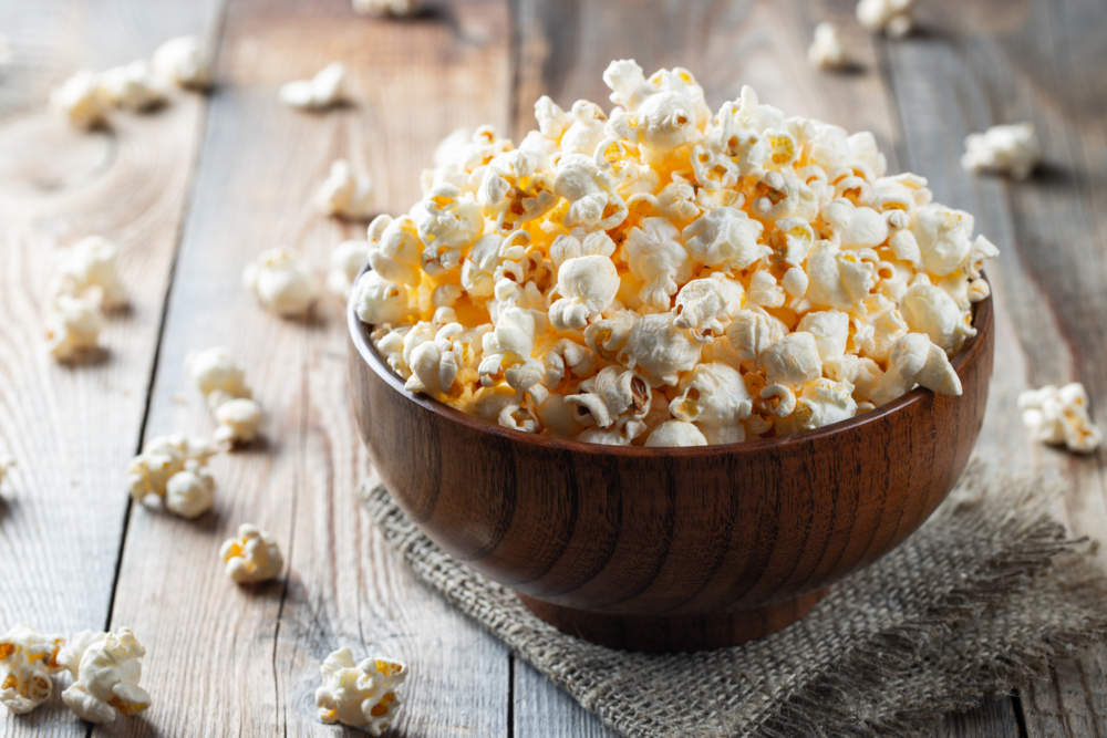 A Wooden Bowl Of Salted Popcorn At The Old Wooden Table. Dark Background. Selective Focus