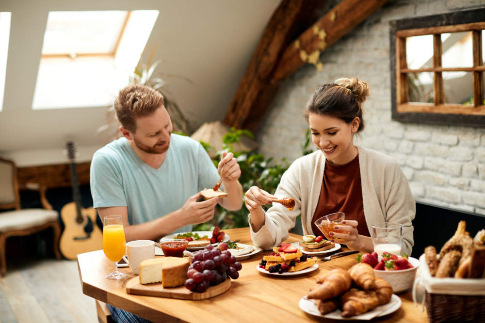 Young Happy Couple Enjoying In Breakfast At Dining Table At Home.