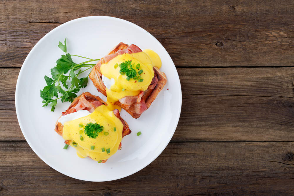 Eggs Benedict With Bacon On Wooden Background . Top View