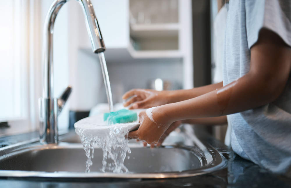 Hands, Sink And Washing Dishes With A Person In The Kitchen Of A Home To Wash A Plate For Hygiene. Water, Bacteria And Soap With An Adult Cleaning Porcelain Crockery In A House To Clean For Housework