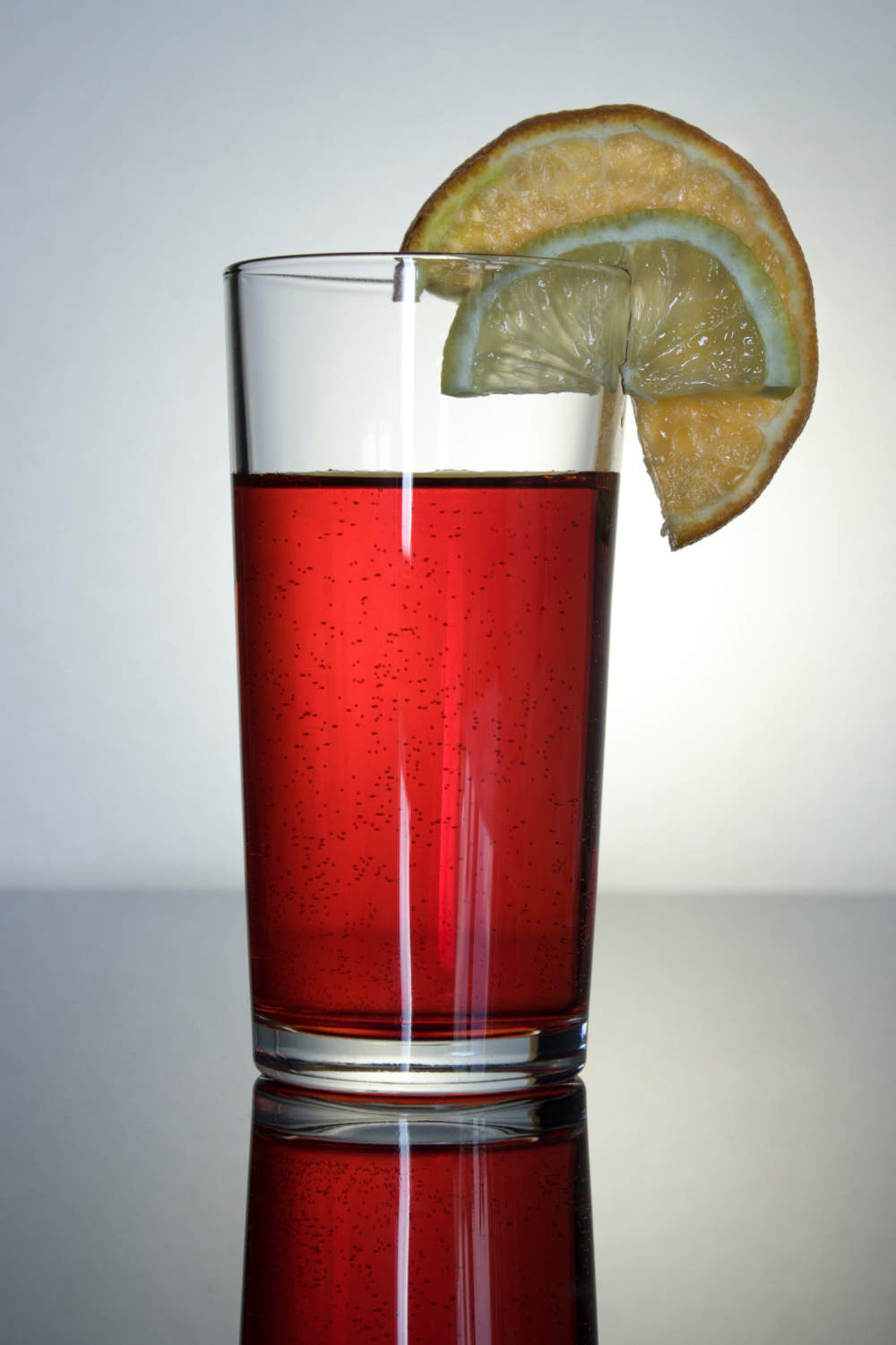 Pink Drink In A Glass Glass Cup With Reflection, A Slice Of Lemon And Orange