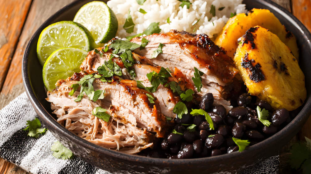 Mouthwatering Cuban Mojo Pork With Citrus, Garlic, Rice, And Black Beans On A Rustic Wooden Table