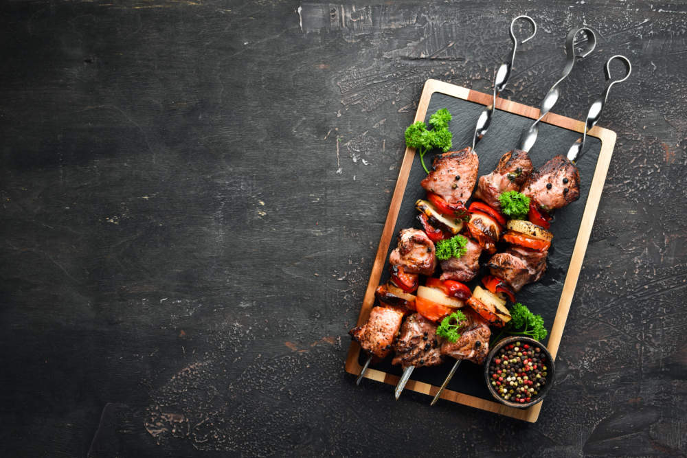 Shish Kebab Bbq Meat With Onions And Tomatoes. On A Black Background. Top View. Free Space For Your Text. Rustic Style.