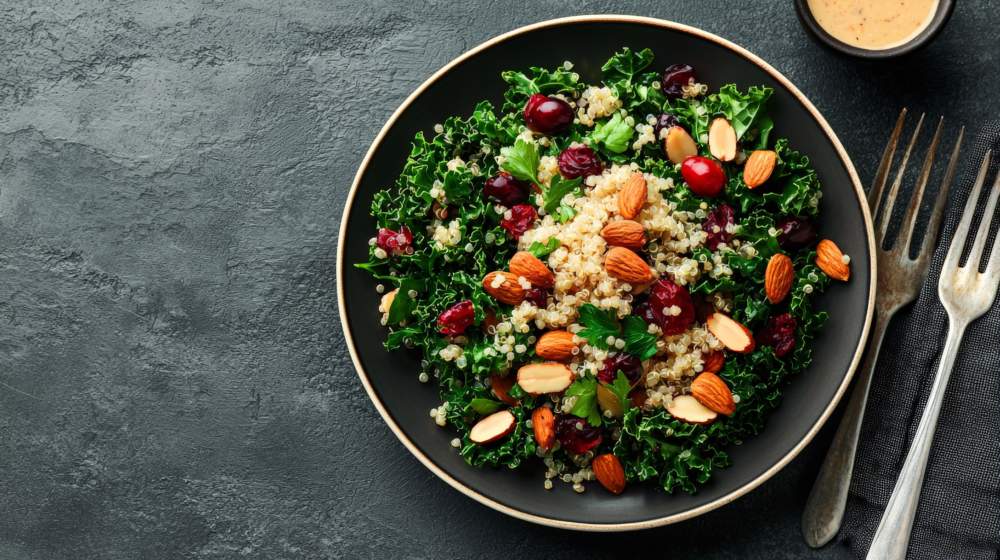A Healthy Kale And Quinoa Salad With Roasted Almonds, Cranberries, And A Citrus Vinaigrette, Beautifully Arranged On A Ceramic Plate