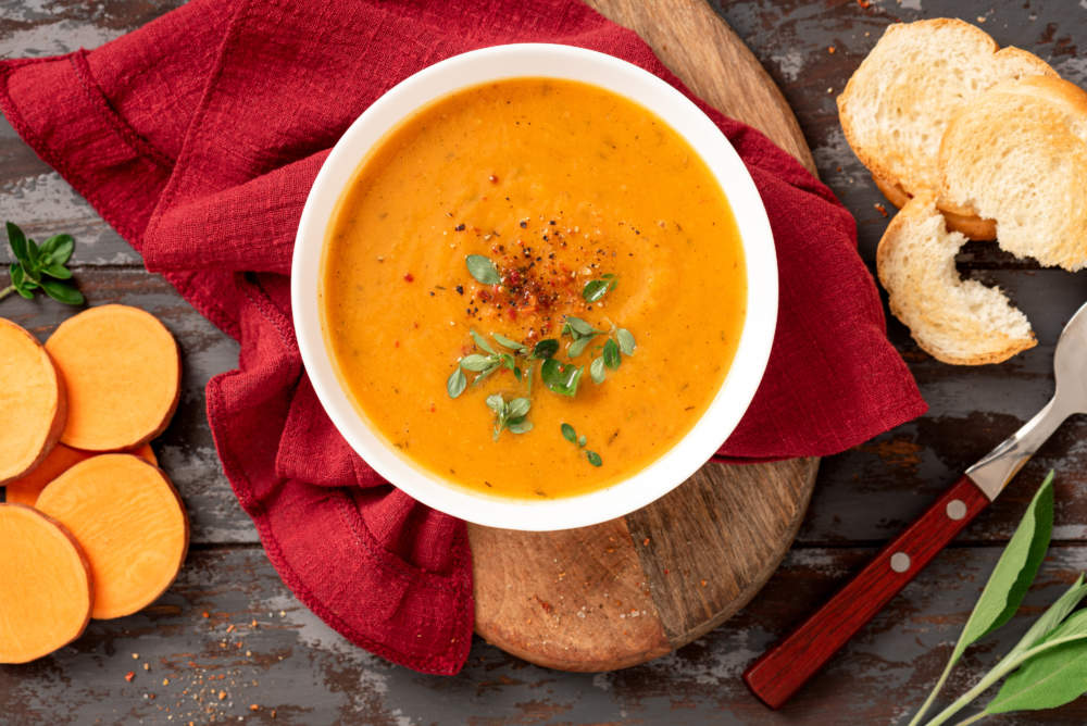 Creamy Sweet Potato Soup With Carrots And Spices In A White Bowl On A Dark Background Top View. Tasty Vegan Sweet Potato Soup, Autumn Food.